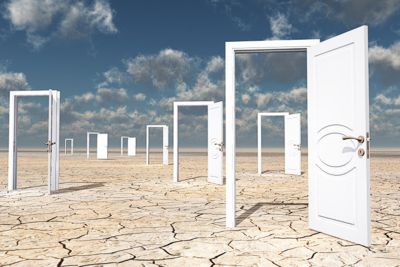 Weiße Türrahmen, die ins Nirgendwo führen, über einem Wüstenboden mit geöffneten Türen positioniert - © 123rf.com / rolffimages